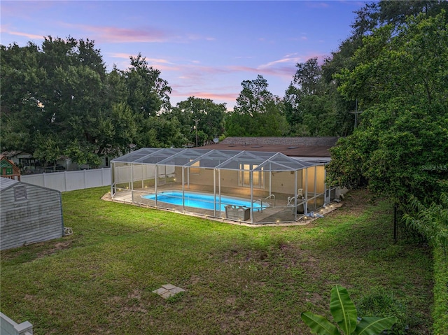 yard at dusk featuring a fenced in pool and glass enclosure