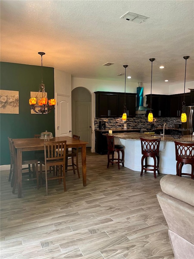 dining room with sink, light hardwood / wood-style floors, and a textured ceiling