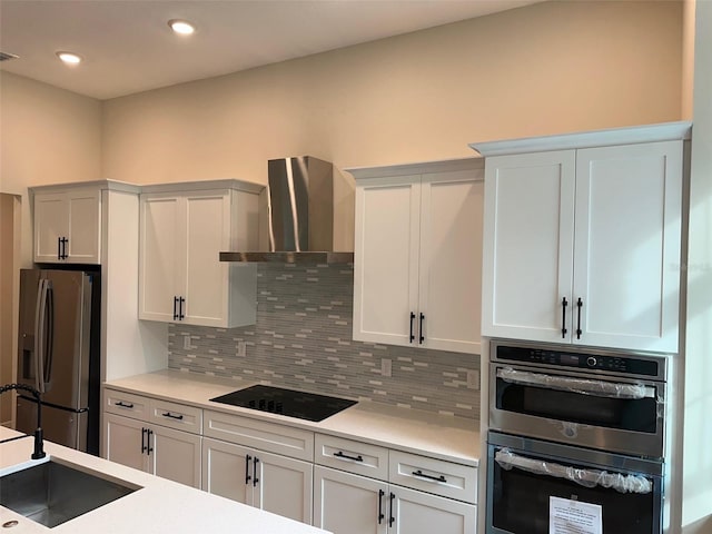 kitchen featuring white cabinetry, wall chimney range hood, appliances with stainless steel finishes, and tasteful backsplash