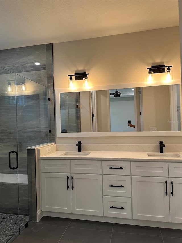 bathroom with ceiling fan, vanity, a shower with door, and tile patterned floors