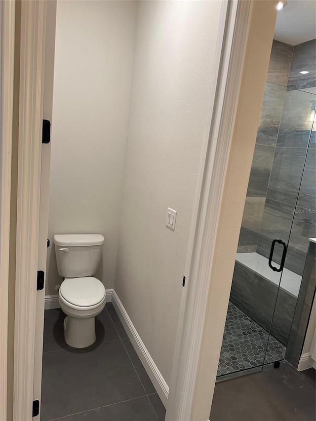 bathroom with toilet, tile patterned flooring, and a shower with shower door