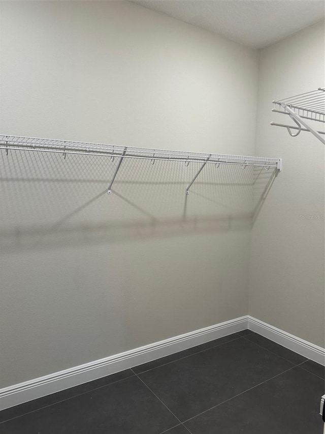 walk in closet featuring dark tile patterned flooring