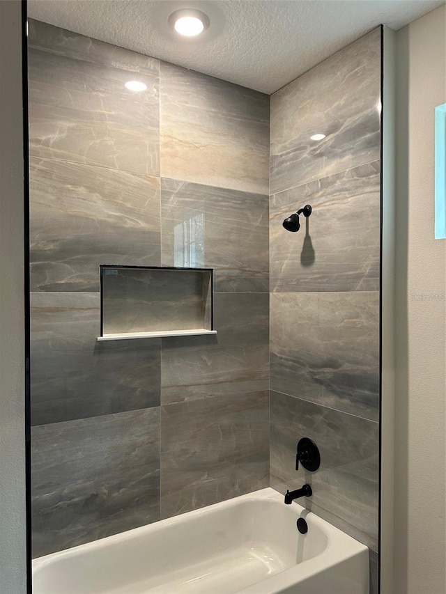 bathroom featuring tiled shower / bath and a textured ceiling