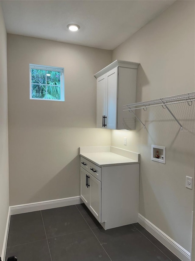 laundry area featuring dark tile patterned flooring, washer hookup, and cabinets