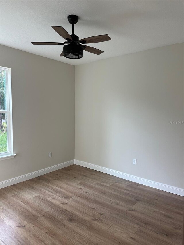 unfurnished room with ceiling fan, wood-type flooring, and a textured ceiling