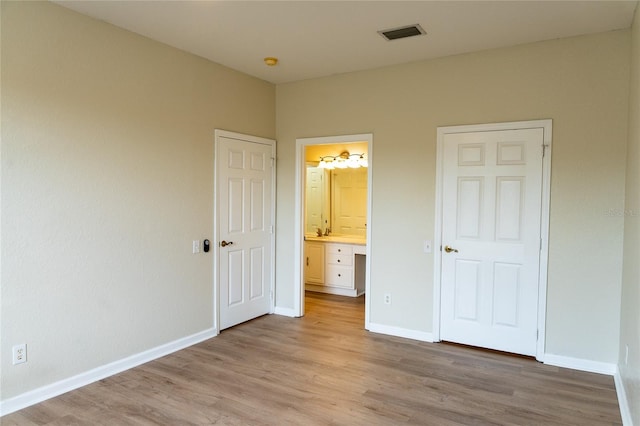 unfurnished bedroom featuring light hardwood / wood-style flooring and ensuite bathroom