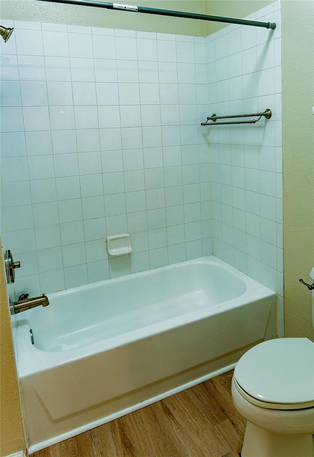 bathroom featuring toilet, tiled shower / bath combo, and hardwood / wood-style flooring