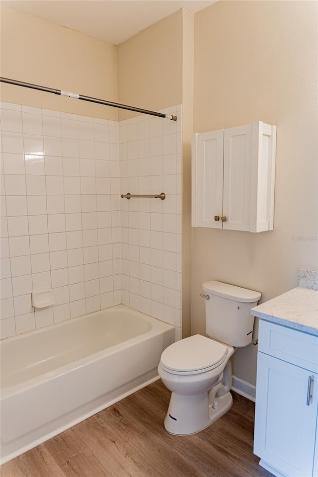 full bathroom featuring hardwood / wood-style floors, tiled shower / bath, toilet, and vanity