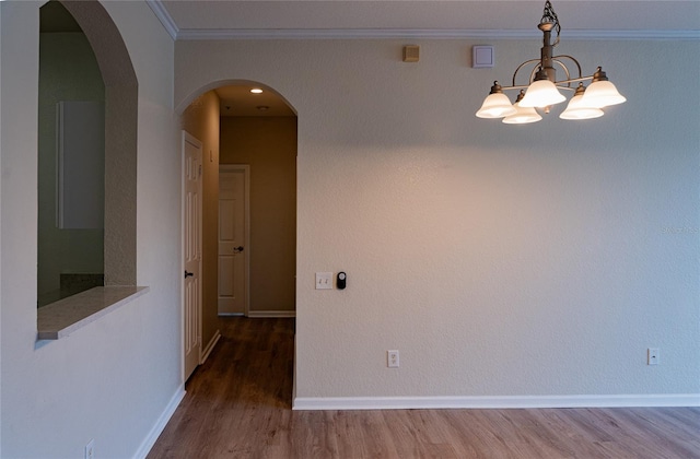 unfurnished room with crown molding, a notable chandelier, and wood-type flooring