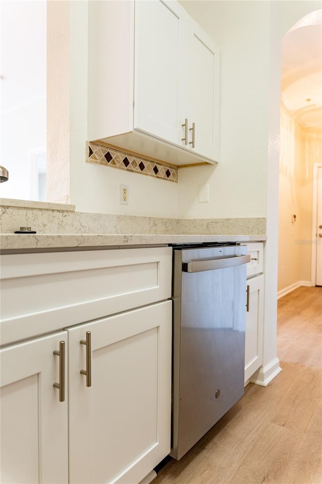 kitchen with light hardwood / wood-style flooring, stainless steel dishwasher, and white cabinetry