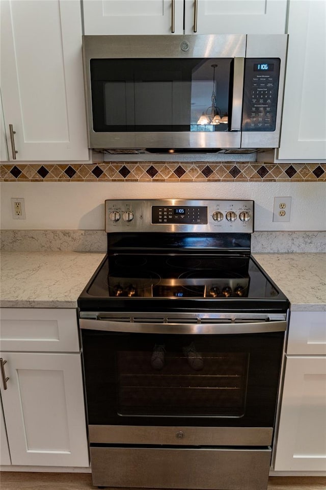 kitchen with appliances with stainless steel finishes, white cabinets, and decorative backsplash