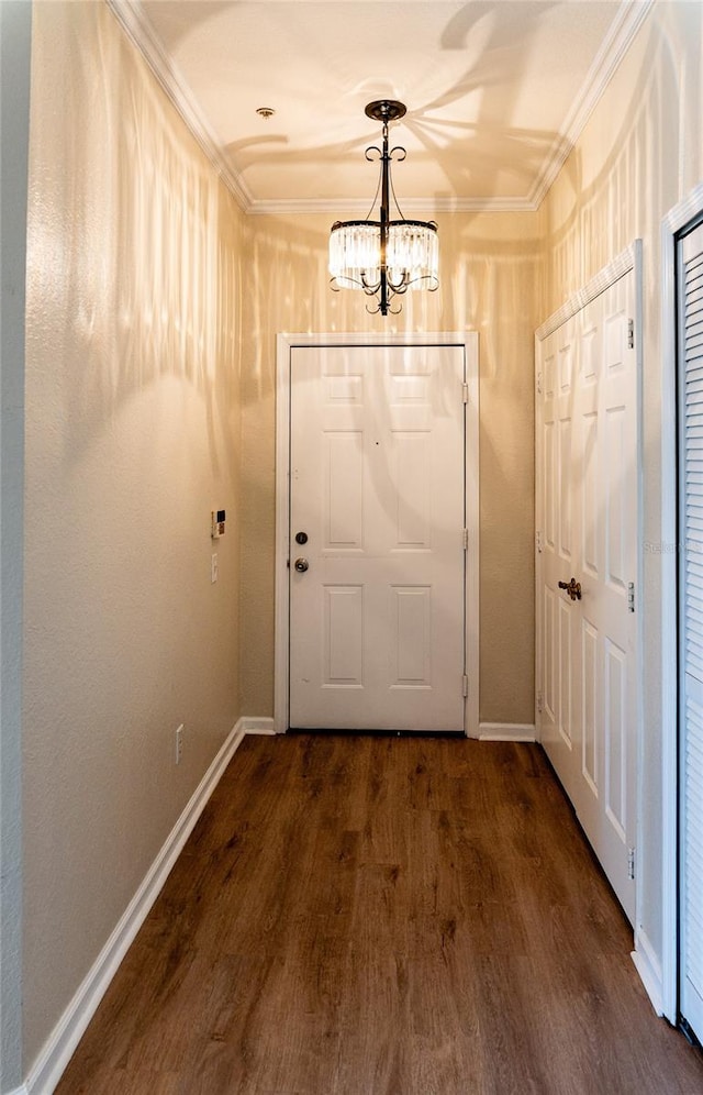 doorway featuring dark wood-type flooring, a chandelier, and ornamental molding