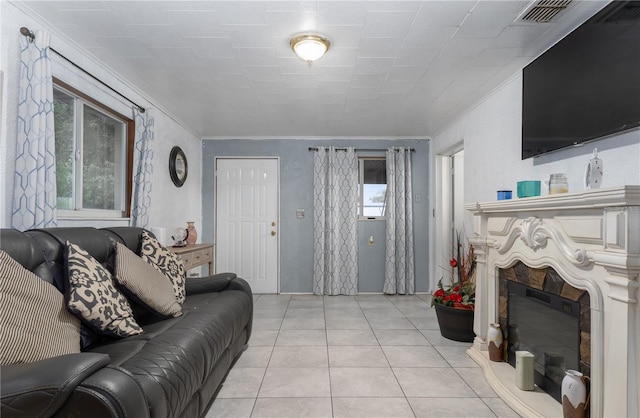 living room featuring light tile patterned floors, crown molding, and a premium fireplace