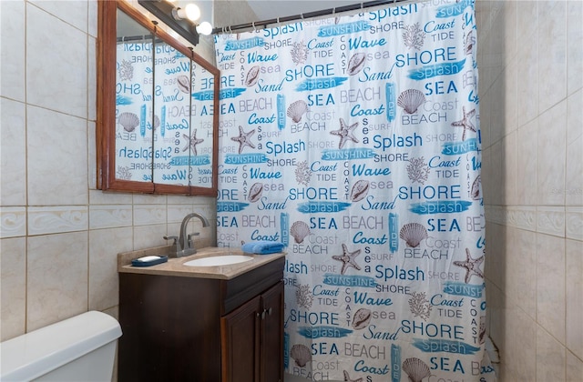 bathroom with vanity, toilet, curtained shower, and tile walls