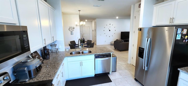 kitchen with light tile patterned floors, appliances with stainless steel finishes, a notable chandelier, white cabinetry, and sink