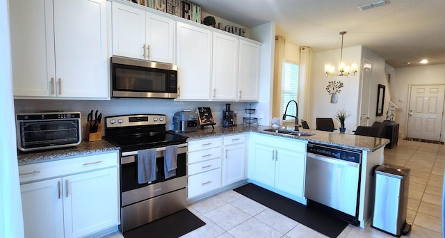 kitchen with dark stone counters, appliances with stainless steel finishes, sink, and white cabinets