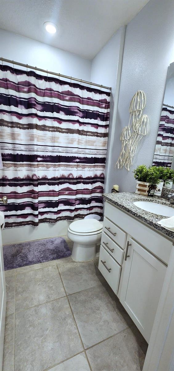 bathroom with vanity, toilet, a shower with shower curtain, and tile patterned flooring