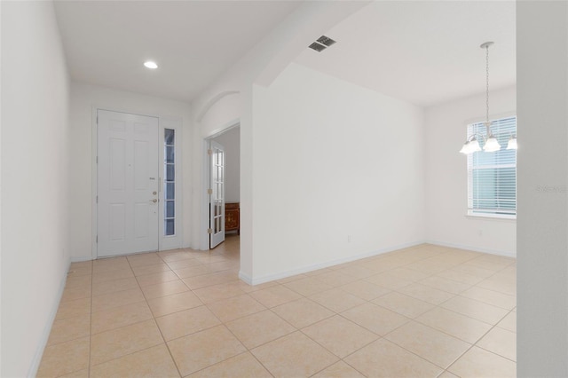 tiled foyer featuring an inviting chandelier