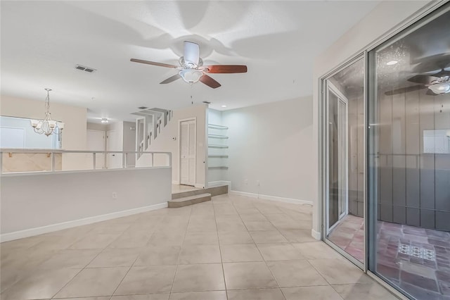 unfurnished living room with ceiling fan with notable chandelier and light tile patterned floors