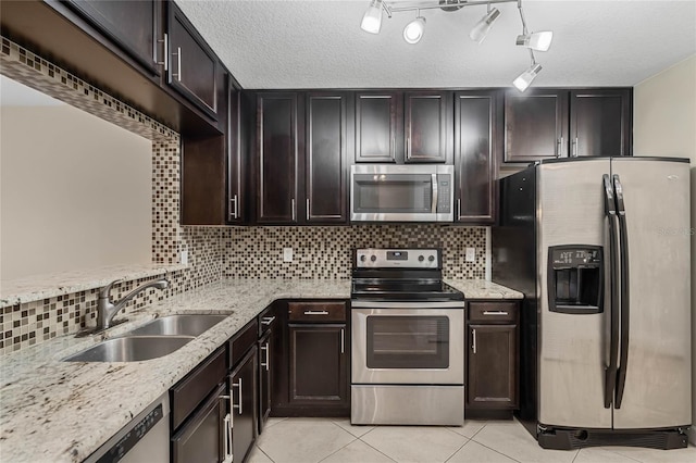 kitchen with light tile patterned floors, a textured ceiling, stainless steel appliances, and dark brown cabinetry