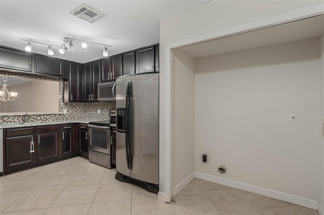 kitchen featuring appliances with stainless steel finishes, a chandelier, backsplash, and light tile patterned floors