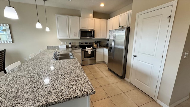 kitchen featuring sink, white cabinets, kitchen peninsula, stainless steel appliances, and decorative light fixtures