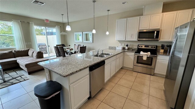 kitchen with appliances with stainless steel finishes, white cabinets, kitchen peninsula, decorative light fixtures, and sink