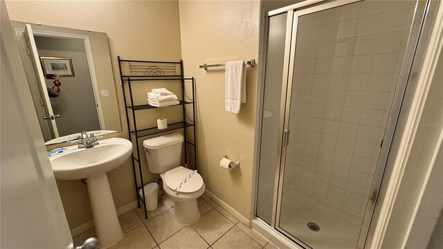 bathroom with a shower with shower door, toilet, and tile patterned flooring