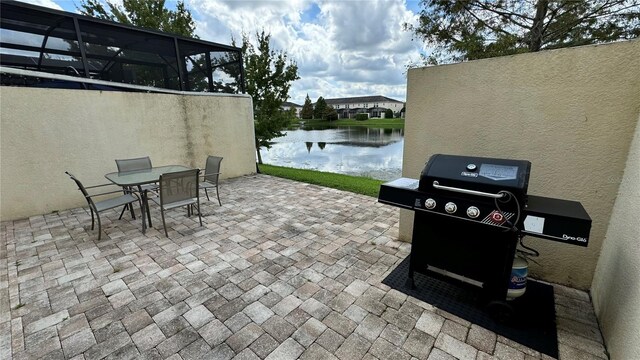 view of patio / terrace featuring glass enclosure, a water view, and a grill