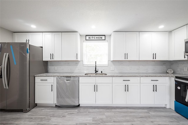 kitchen with light hardwood / wood-style flooring, white cabinets, appliances with stainless steel finishes, and sink