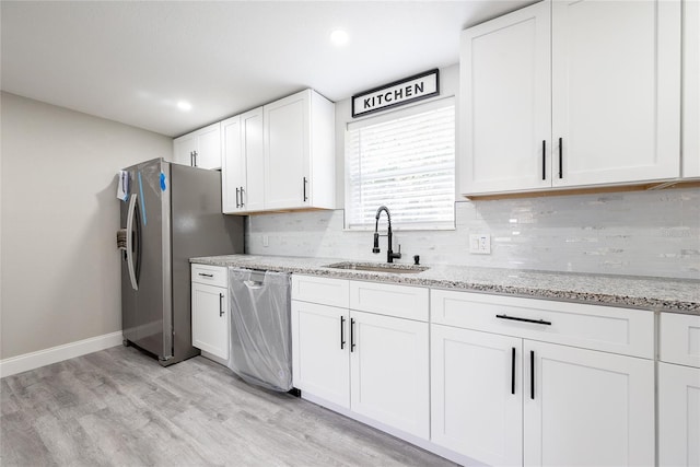 kitchen with light hardwood / wood-style flooring, light stone counters, sink, appliances with stainless steel finishes, and white cabinets