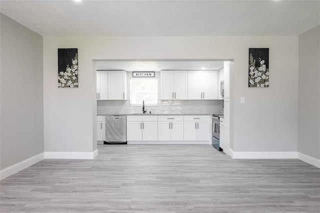 kitchen with tasteful backsplash, light hardwood / wood-style flooring, light stone countertops, appliances with stainless steel finishes, and white cabinets