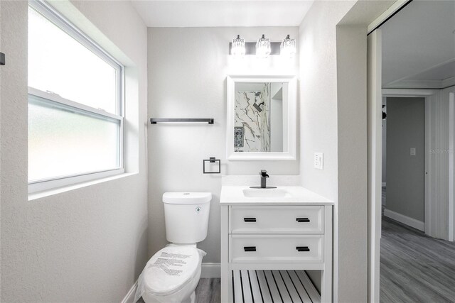 bathroom featuring vanity, toilet, a healthy amount of sunlight, and hardwood / wood-style floors