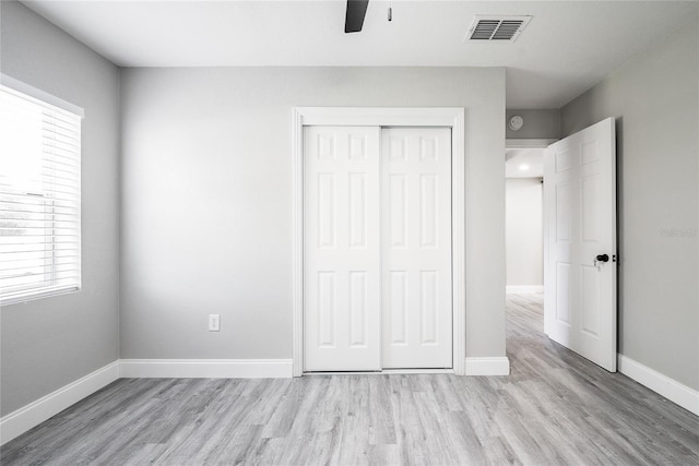 unfurnished bedroom featuring light wood-type flooring, a closet, and ceiling fan