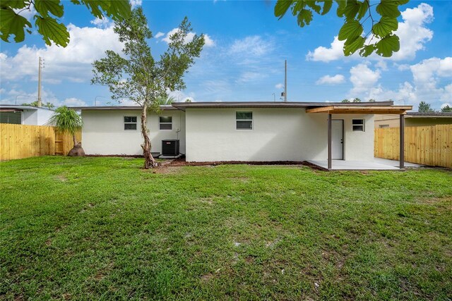 rear view of property featuring central AC unit, a yard, and a patio