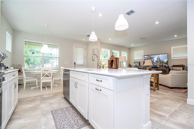 kitchen with dishwasher, a healthy amount of sunlight, hanging light fixtures, an island with sink, and white cabinetry