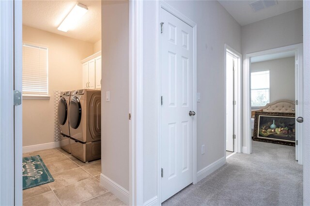 washroom featuring cabinets, washing machine and clothes dryer, and light tile patterned floors