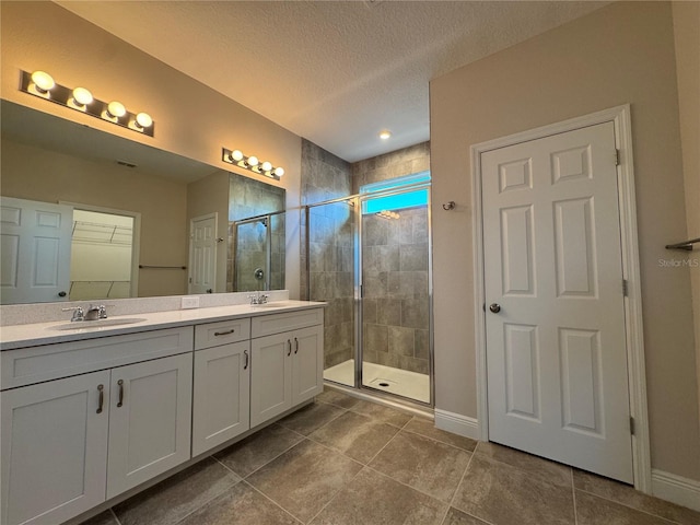 bathroom featuring a textured ceiling, walk in shower, and vanity