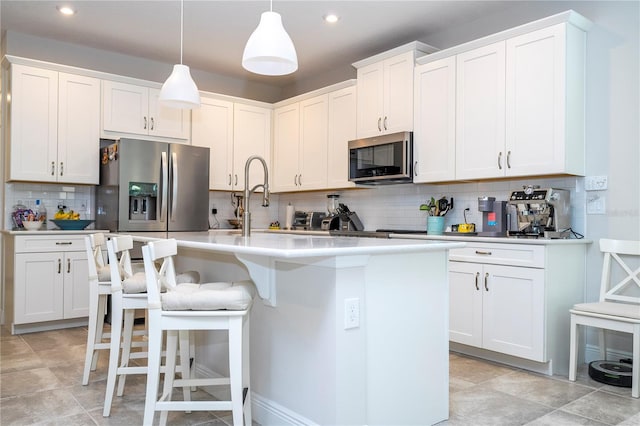 kitchen featuring stainless steel appliances, white cabinets, decorative light fixtures, an island with sink, and decorative backsplash