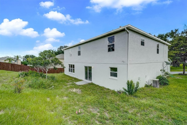 rear view of property with a lawn and cooling unit