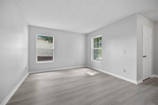 empty room with a textured ceiling and light wood-type flooring