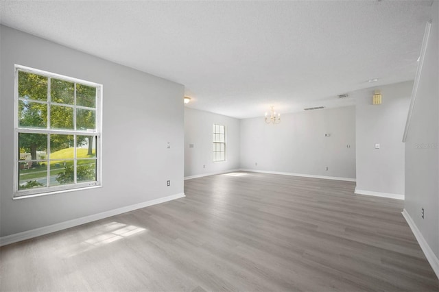 unfurnished room featuring hardwood / wood-style flooring, plenty of natural light, and a textured ceiling