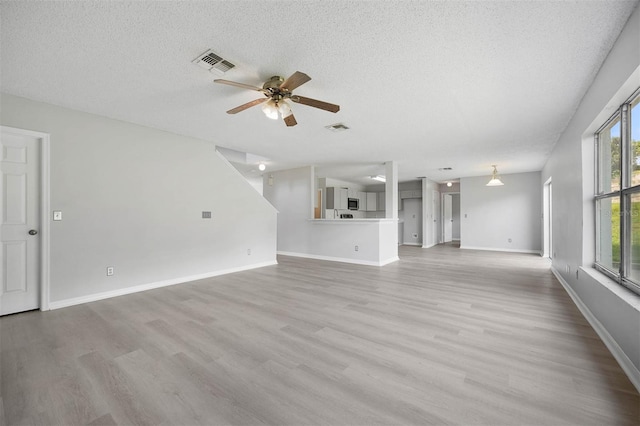 unfurnished living room with light wood-type flooring, a textured ceiling, and ceiling fan