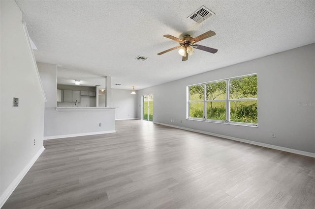 unfurnished living room featuring a textured ceiling, ceiling fan, and hardwood / wood-style floors