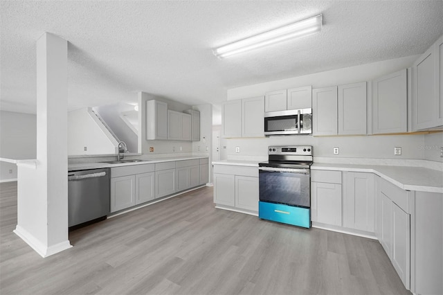 kitchen featuring a textured ceiling, stainless steel appliances, sink, and light hardwood / wood-style floors