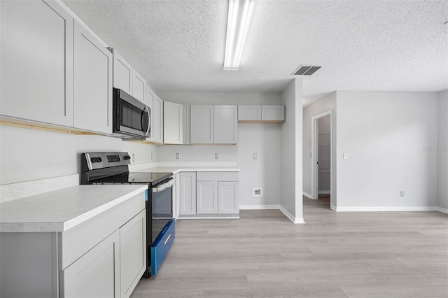 kitchen with appliances with stainless steel finishes, light hardwood / wood-style floors, and a textured ceiling