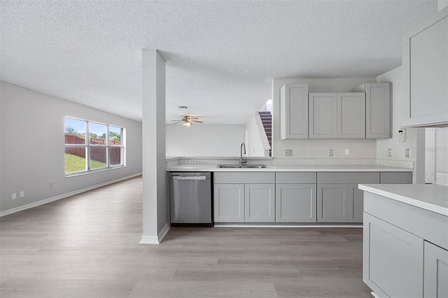 kitchen featuring light wood-type flooring, a textured ceiling, dishwasher, sink, and ceiling fan