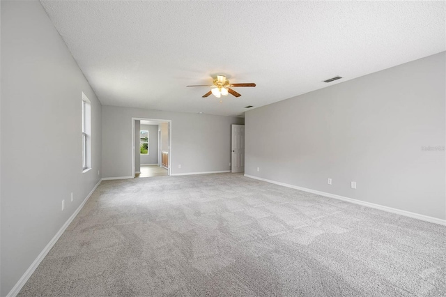 unfurnished room with ceiling fan, light carpet, and a textured ceiling