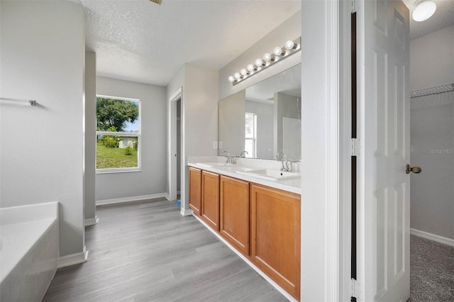 bathroom featuring a tub, wood-type flooring, a textured ceiling, and vanity