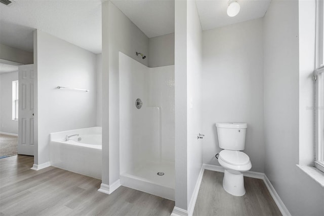 bathroom featuring plus walk in shower, plenty of natural light, toilet, and hardwood / wood-style flooring